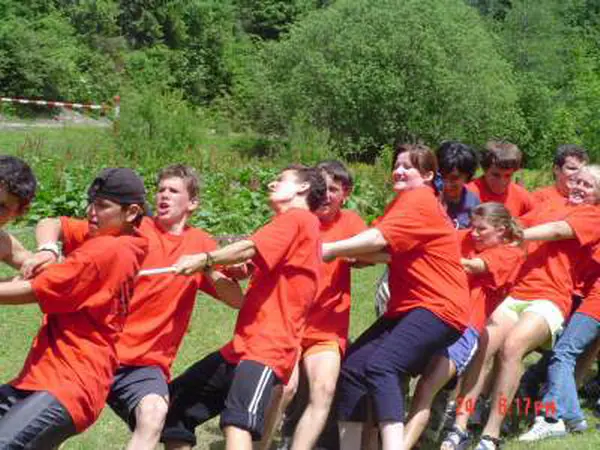 Team in orange T-shirts pulling hard in a tug-of-war contest