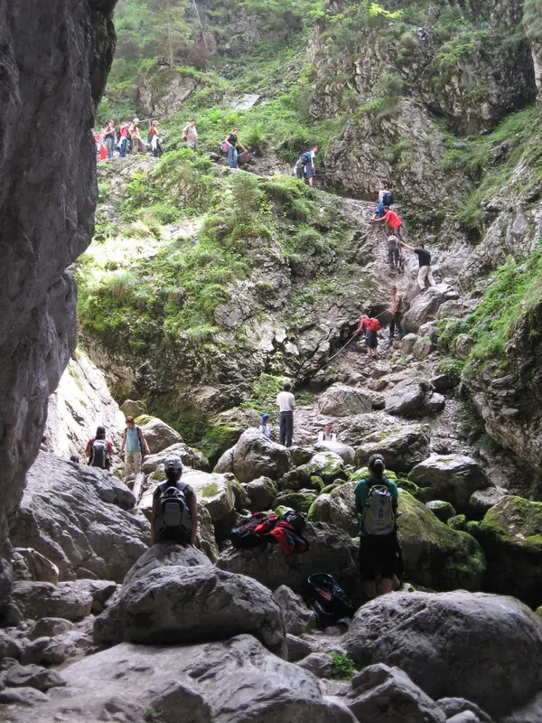 Line of hikers climbing a boulder-strewn gorge between steep cliffs