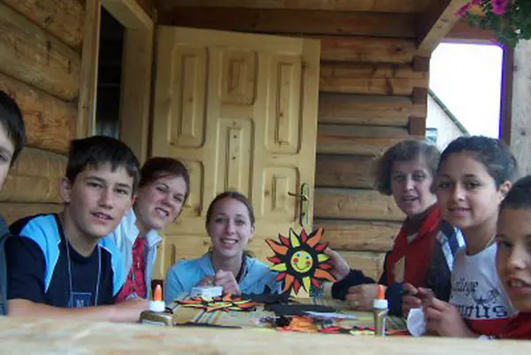 Children making colourful crafts at a table on a wooden porch