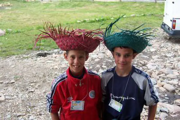 Two boys wearing colourful woven straw hats they made