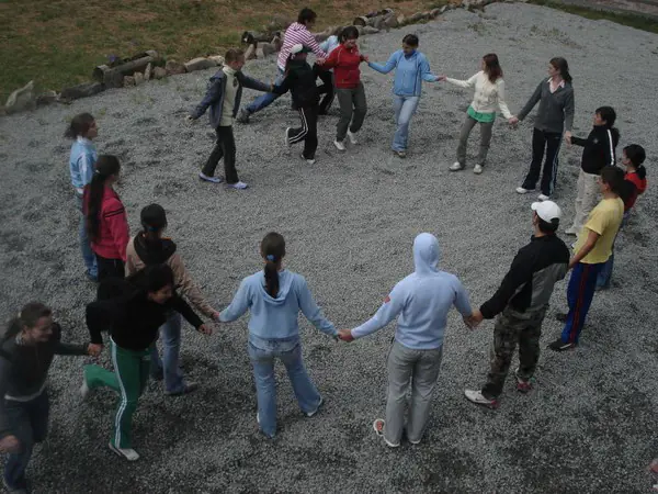 Campers holding hands in a big circle game on the gravel yard