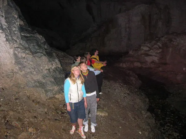 Campers with headlamps exploring a wide cave passage