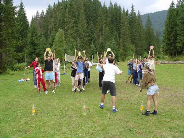 Teams playing an outdoor ball game on a meadow surrounded by fir forest