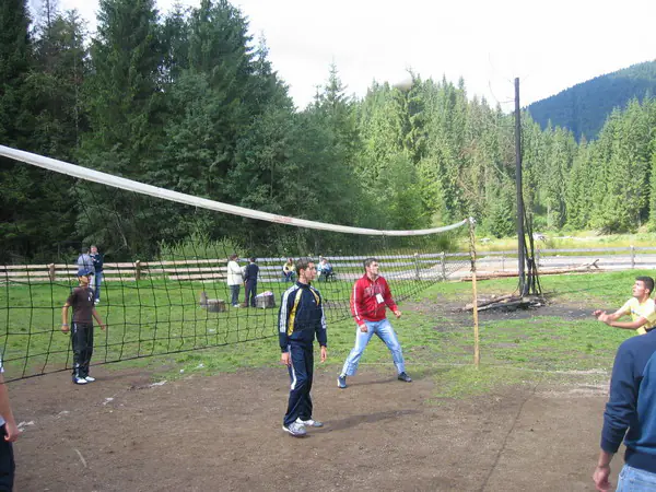 Players at the volleyball net on the camp sports field by the forest