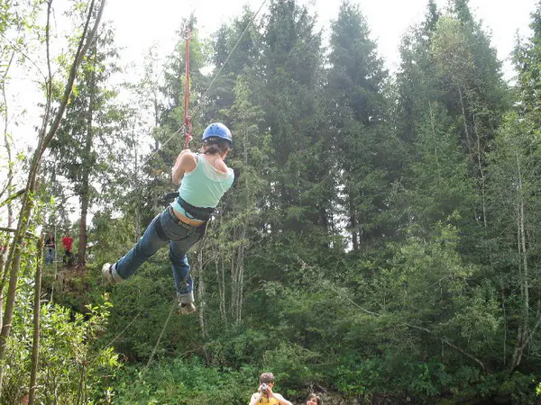 Girl in a helmet gliding down the zip line through the forest