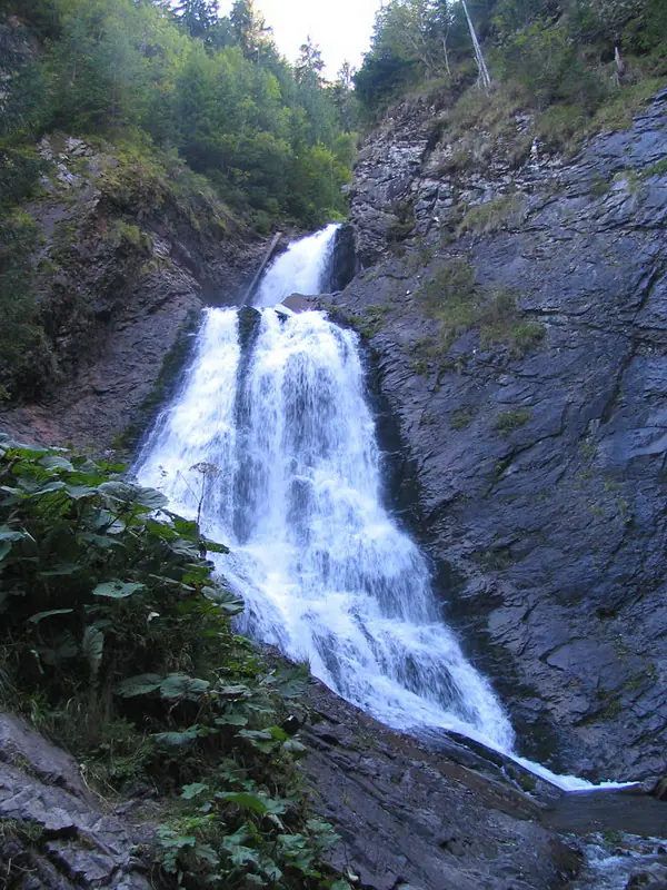 Vălul Miresei Waterfall cascading down dark rock walls in the forest