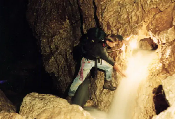 Caver climbing beside an underground waterfall in Cetățile Ponorului cave