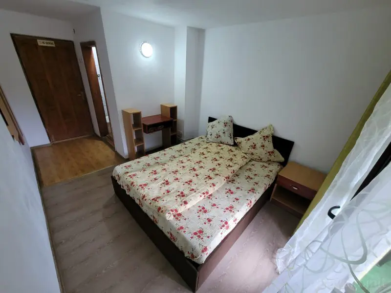 Bright double room with floral bedding, a desk and bedside table