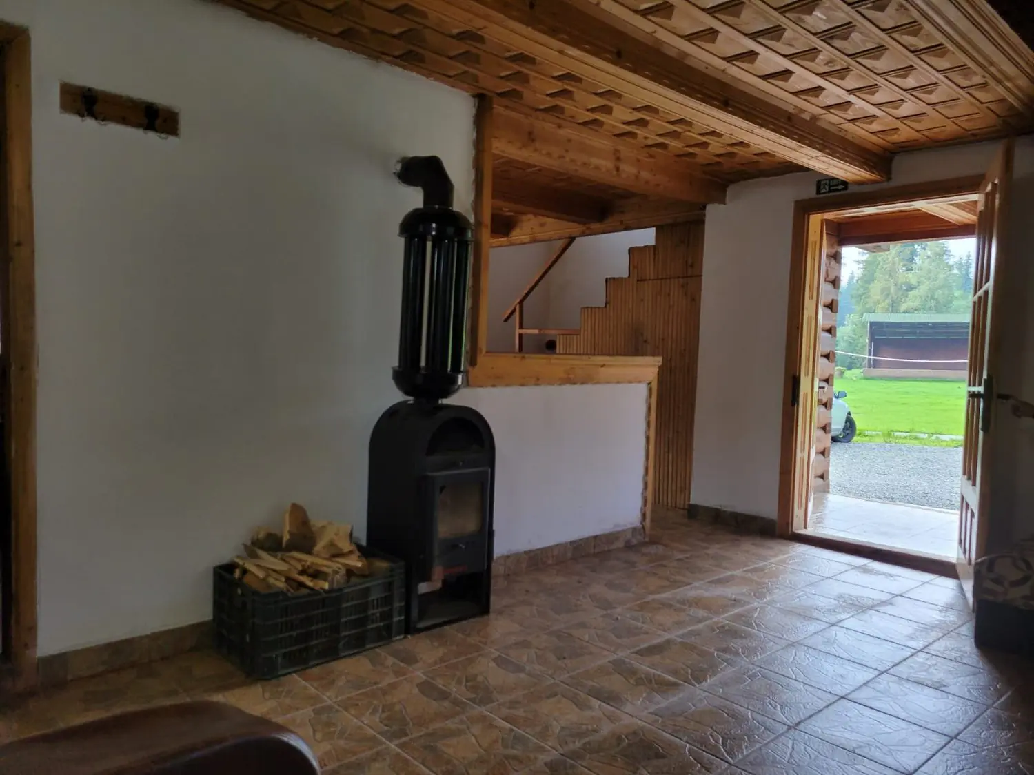 Entrance hall with wood-burning stove, firewood and a wooden staircase