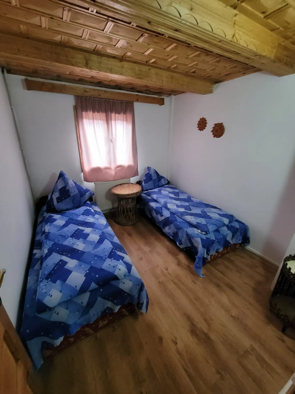 Twin bedroom with blue bedspreads, white walls and a wooden-beamed ceiling