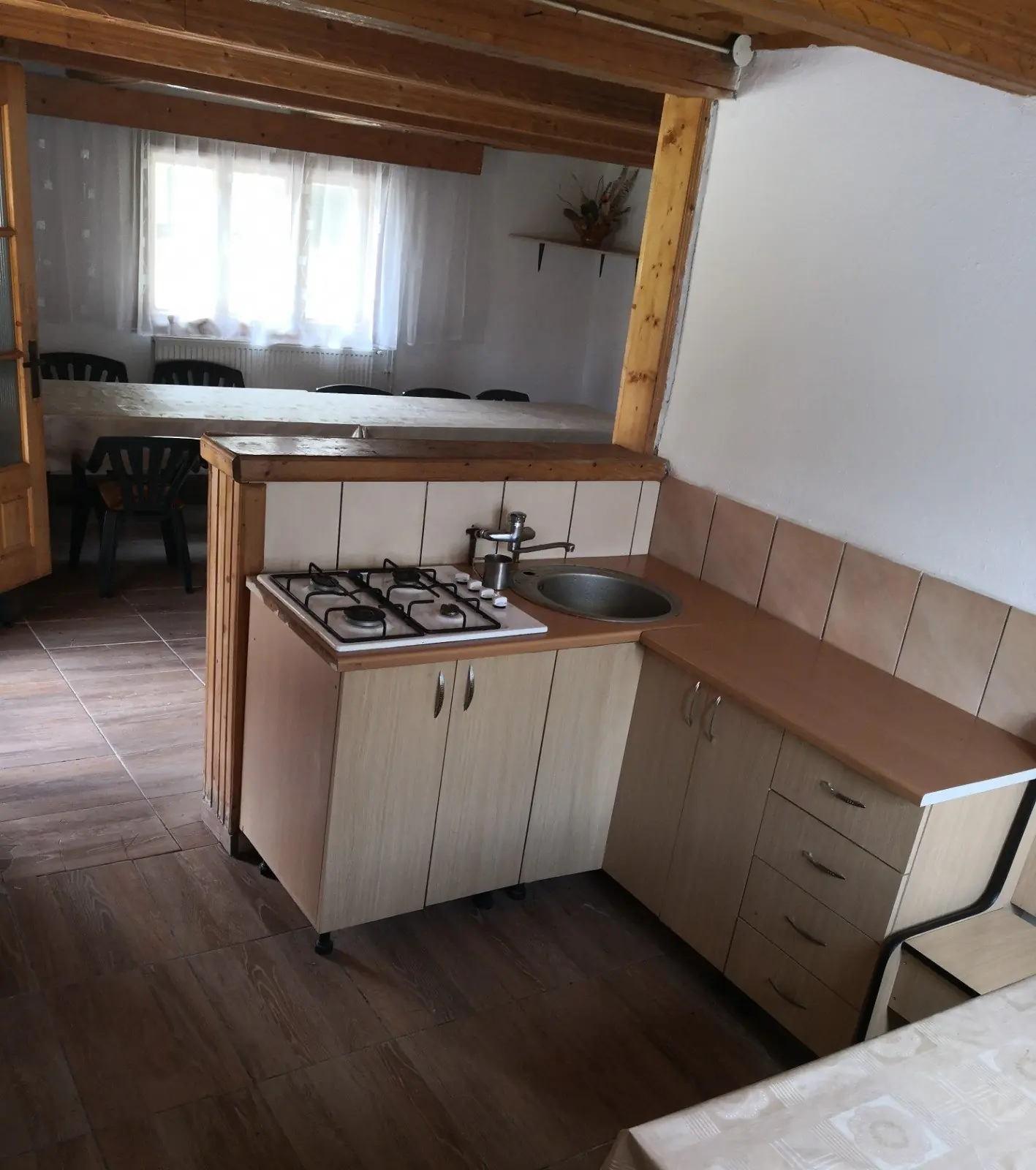 Small kitchenette with gas hob, sink and cupboards, next to the dining area